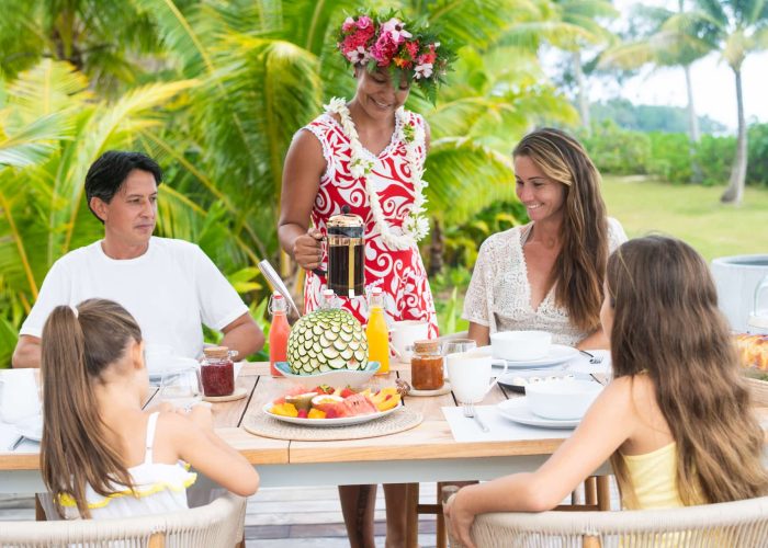 Motu Nao Nao, île privée à Raiatea. Femme polynésienne servant le petit déjeuner à une famille de deux adultes et 2 enfants.