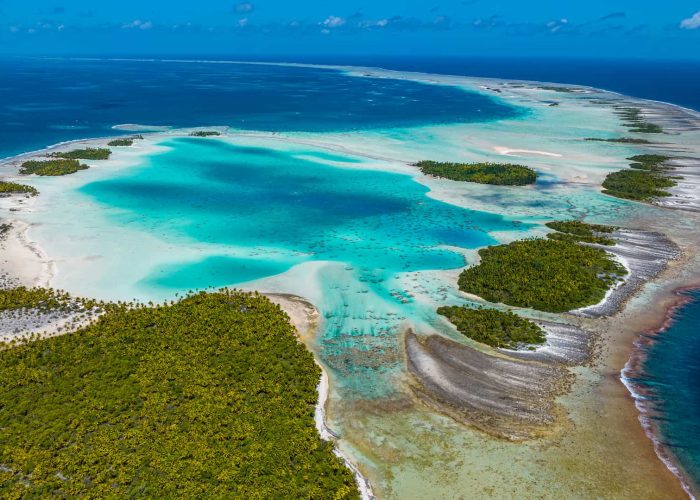 vue aérienne de l'atoll de Rangiroa, au niveau du récif corallien. Vue sur le lagon turquoise et l'océan, ainsi que sur les motus