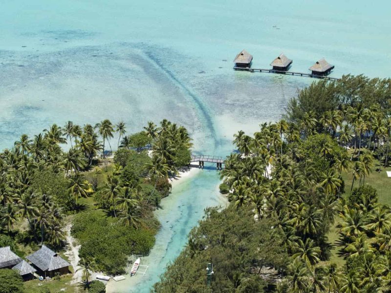 Hôtel Vahine Island 4* à Taha'a. Vue aérienne sur le lagon, la cocoteraie et les 3 bungalows sur pilotis.