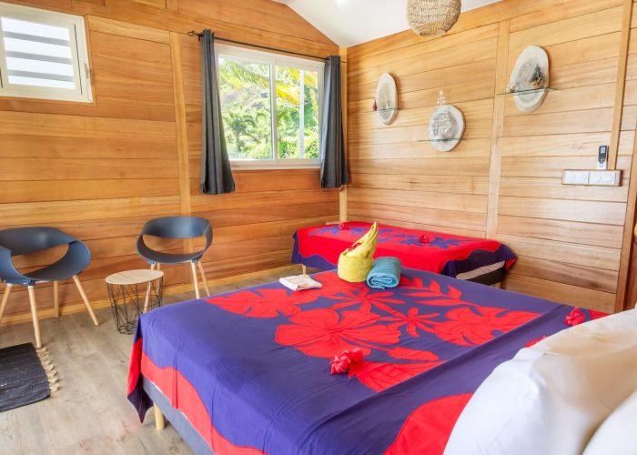 Pension Anahata à Taha’a – intérieur d'un bungalow jardin triple avec tifaifai sur le lit.