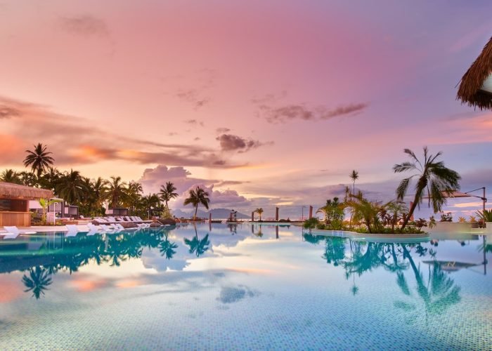 Hôtel Hilton 4* à Tahiti. Vue panoramique piscine au coucher du soleil.