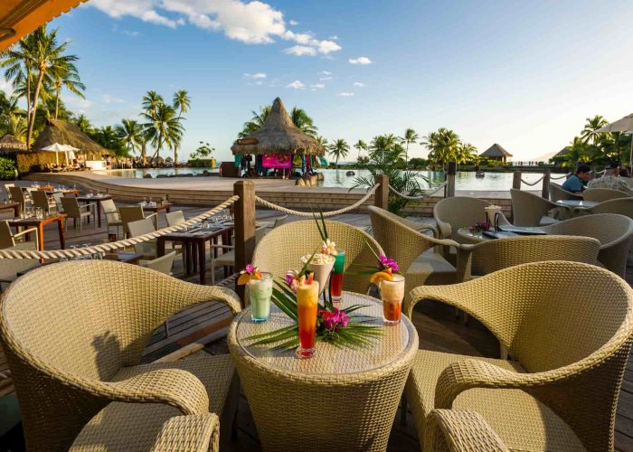 Hôtel Intercontinental Tahiti Resort & Spa 4*. Tiki Bar : 4 cocktails dressés sur une table avec vue sur la piscine principe lors du coucher du soleil.