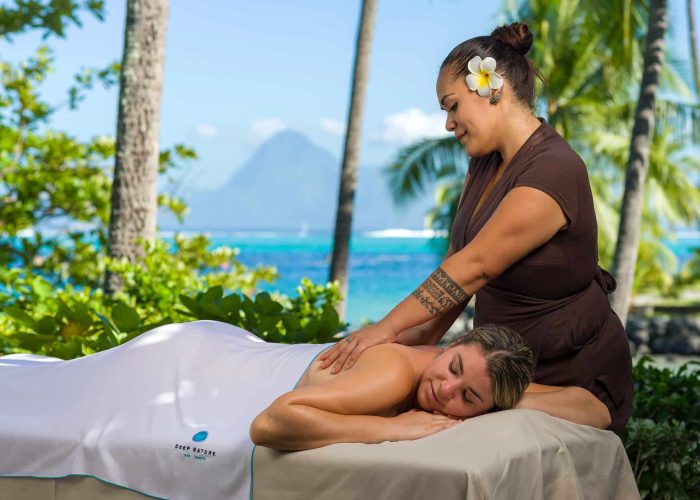 Hôtel Intercontinental Tahiti Resorts & Spa 4* à Tahiti - femme allongée sur une table de massage se vidant masser par une masseuse polynésienne - vue sur le lagon et Moorea en arrière plan