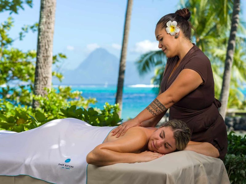 Hôtel Intercontinental Tahiti Resorts & Spa 4* à Tahiti - femme allongée sur une table de massage se vidant masser par une masseuse polynésienne - vue sur le lagon et Moorea en arrière plan