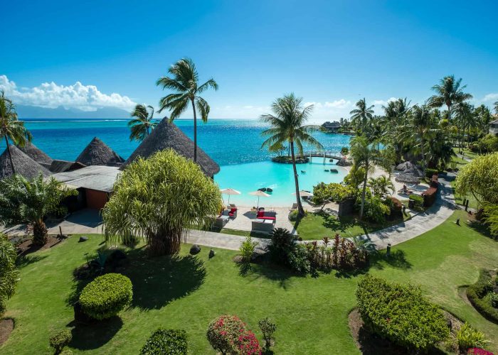 Hôtel Intercontinental Tahiti Resort 4*. Vue depuis une chambre premium, sur la piscine à débordement sur le lagon turquoise. Cocotiers et jardin luxuriant.