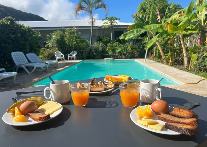 Pension de la Plage à Tahiti - Petit déjeuner dressé sur une table au bord de la piscine.