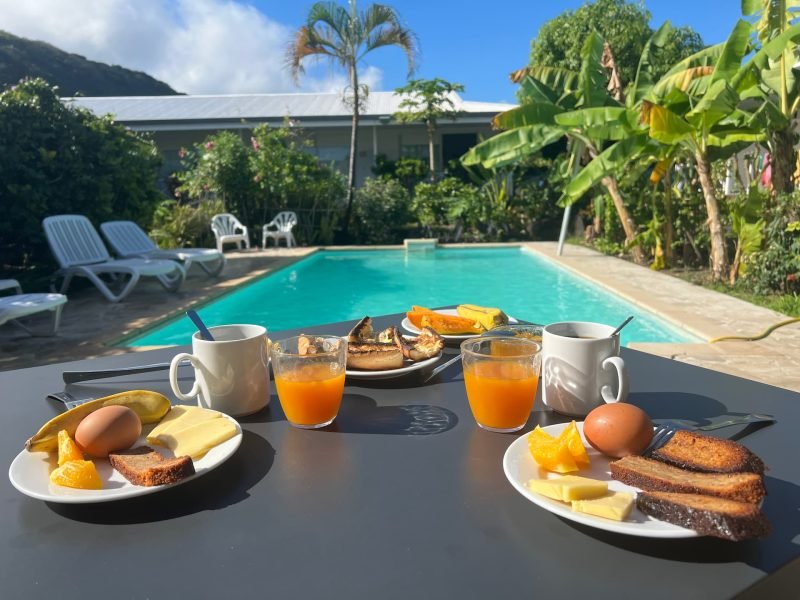 Pension de la Plage à Tahiti - Petit déjeuner dressé sur une table au bord de la piscine.