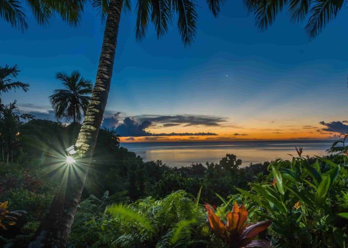 Pension Vanira Lodge à la presqu'île de Tahiti. Vue depuis la pension sur le jardin tropical, et le lagon, au coucher du soleil.