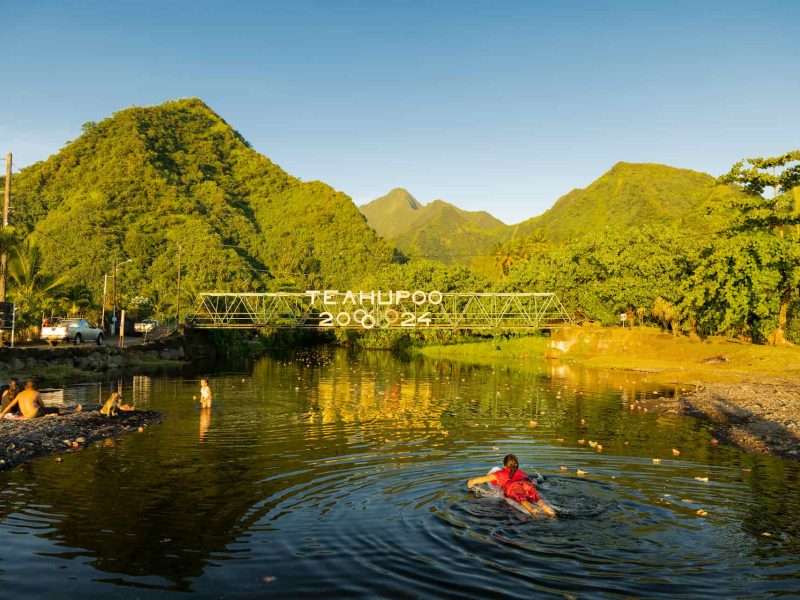 vue du pont de Teahupoo à Tahiti avec surfeuse allongée sur une place et montagne en arrière plan