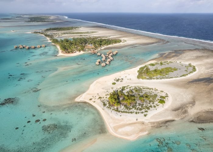 subtiles-tahiti-tikehau-hôtel-le-tikehau-by-pearl-resorts-7©le-tikehau-by-pearl-resorts Hôtel Le Tikehau by Pearl Resorts 4*- vue aérienne sur les motus de Tikehau et l'hôtel. Lagon turquoise et côté récif avec océan à droite.